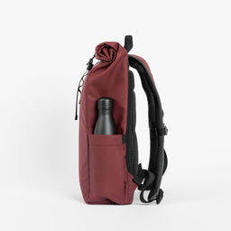 A studio shot of the bottle pocket on a Roll Top Mini backpack in Earth Red
