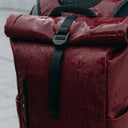 A close up of a Roll Top Mini backpack in Earth Red in rain