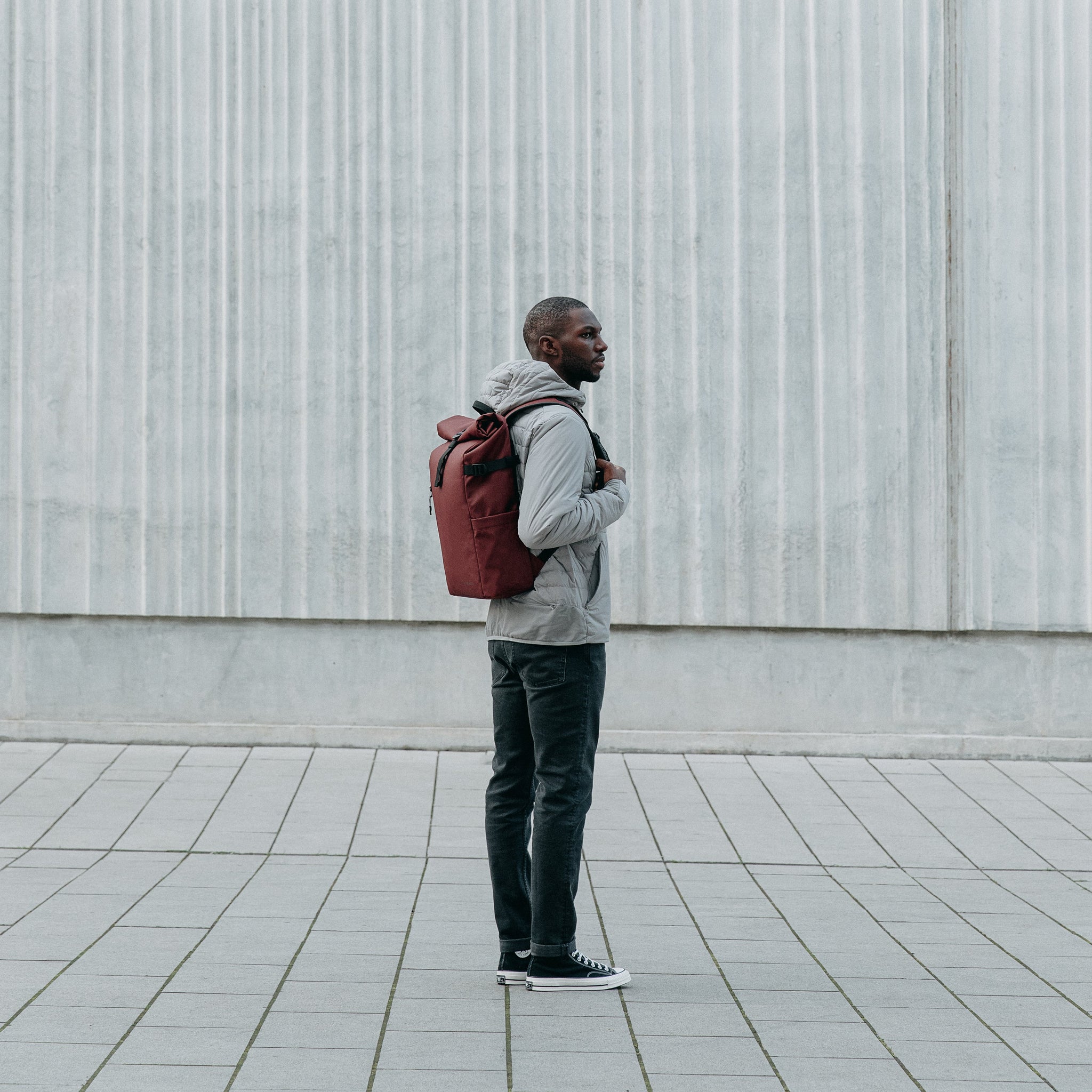 Man wearing Roll Top backpack in Earth Red