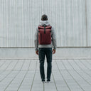 Man wearing Roll Top backpack in Earth Red