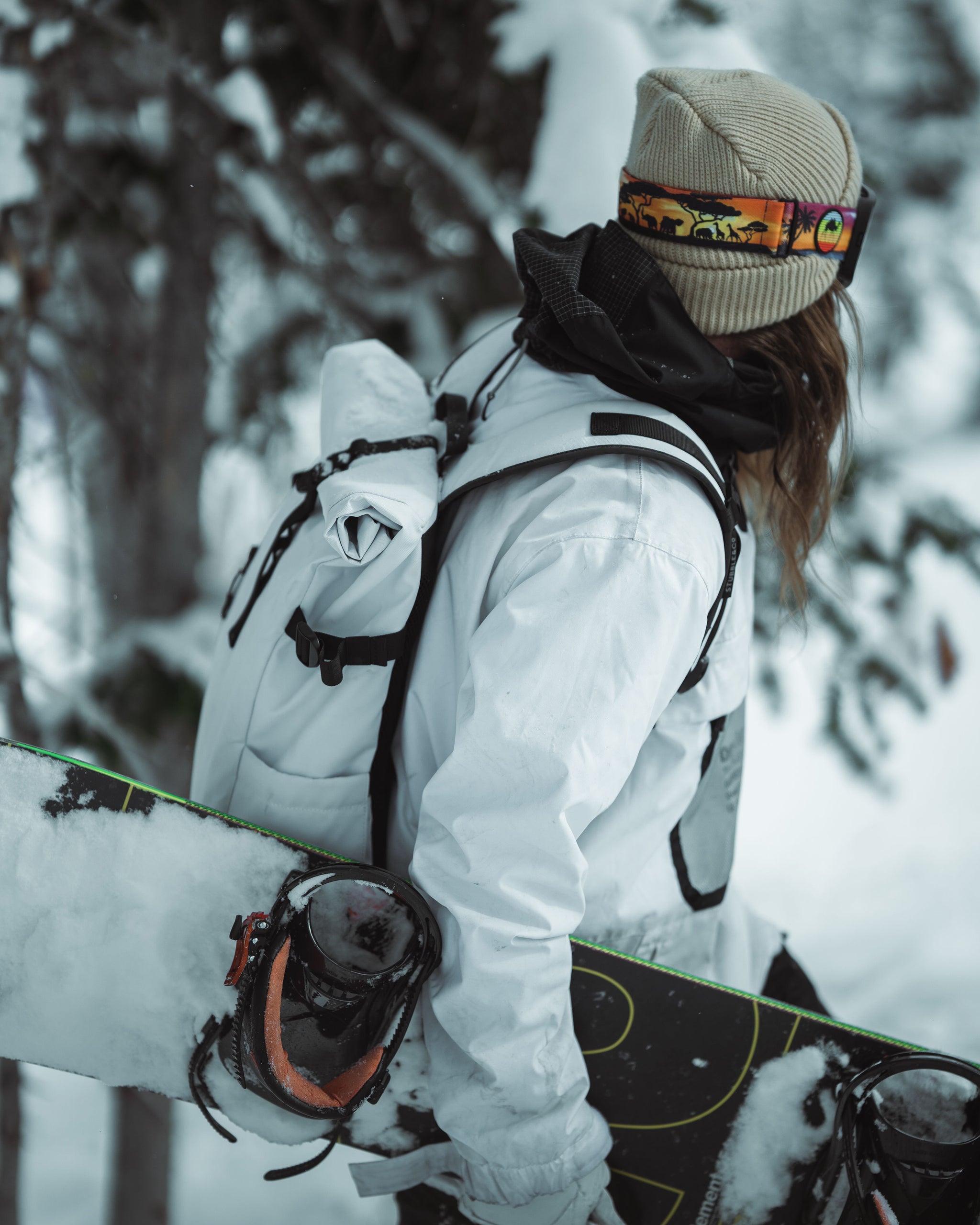 A snowboarder wearing a Stubble & Co Roll Top Backpack in white