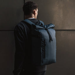 Side angle view of a man looking over his shoulder wearing The Roll Top in Tasmin Blue