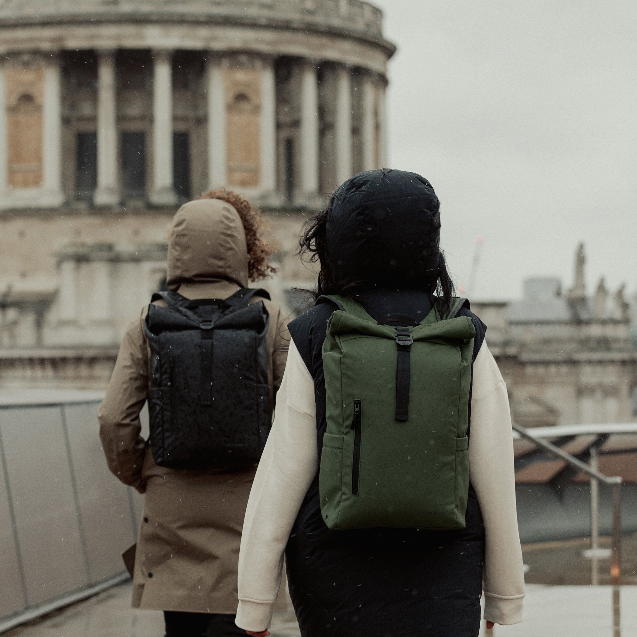 Two people wearing the Roll Top 15L in Urban Green in a city