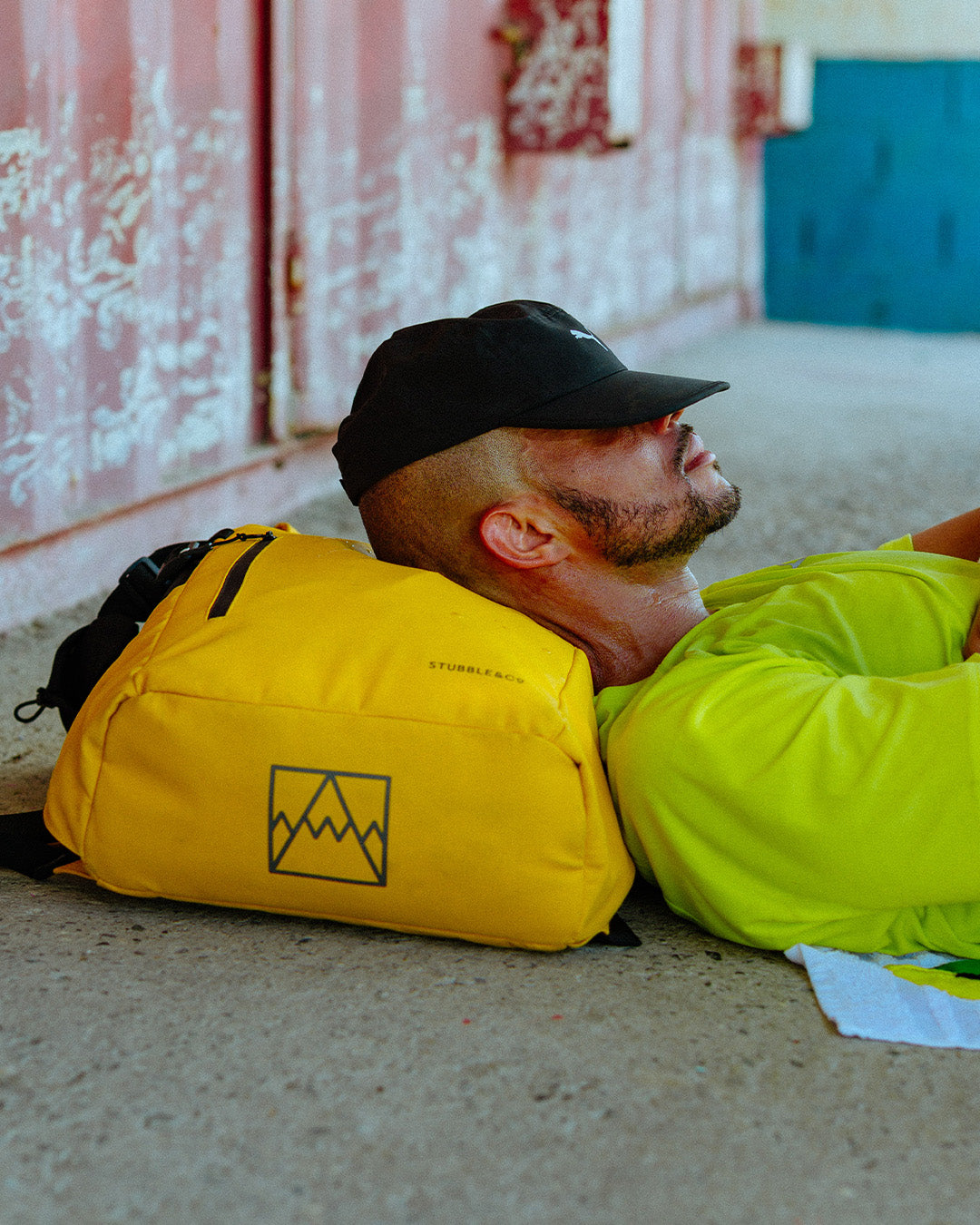Man lying on the ground with a yellow backpack.