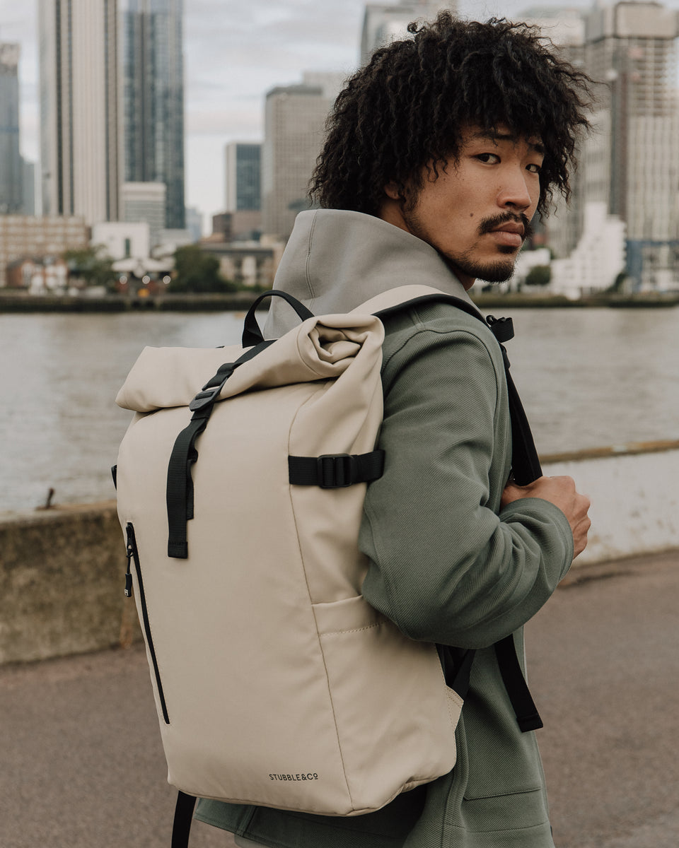 A man wearing a sand roll top on his back in front of his city scape