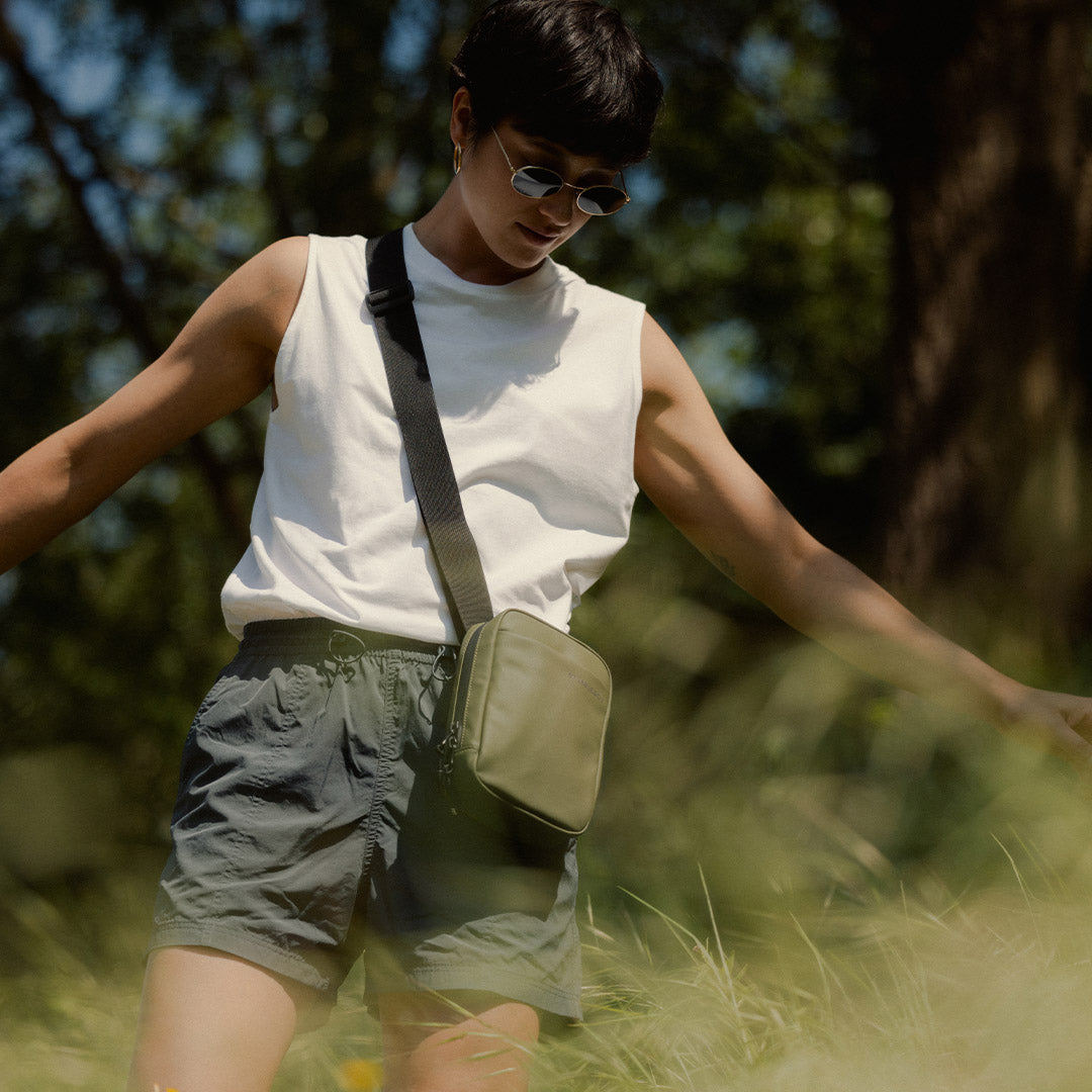 a woman in the grass wearing an Urban Green shoulder bag