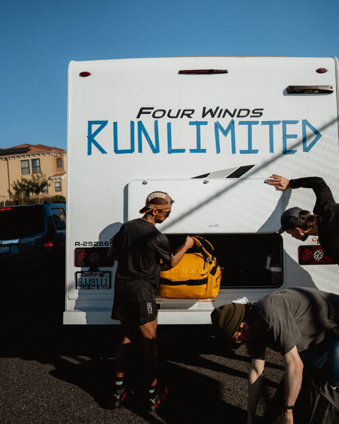 Two people loading a yellow Kit Bag into a white van with 'RunLimited' branding.