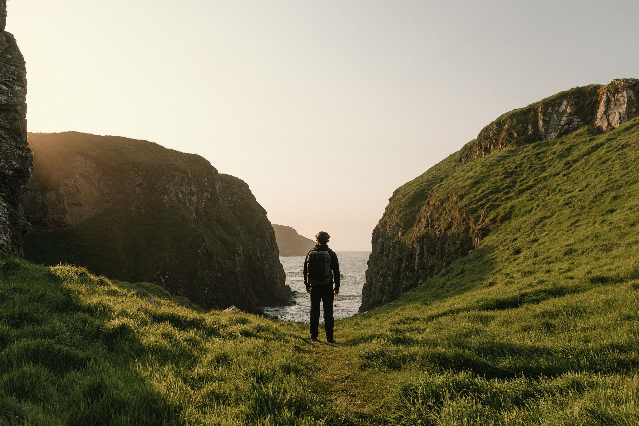 Man in green field with a backpack