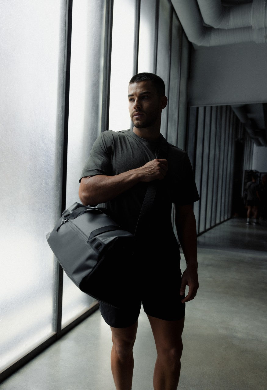 male in sports clothing with a black duffel bag