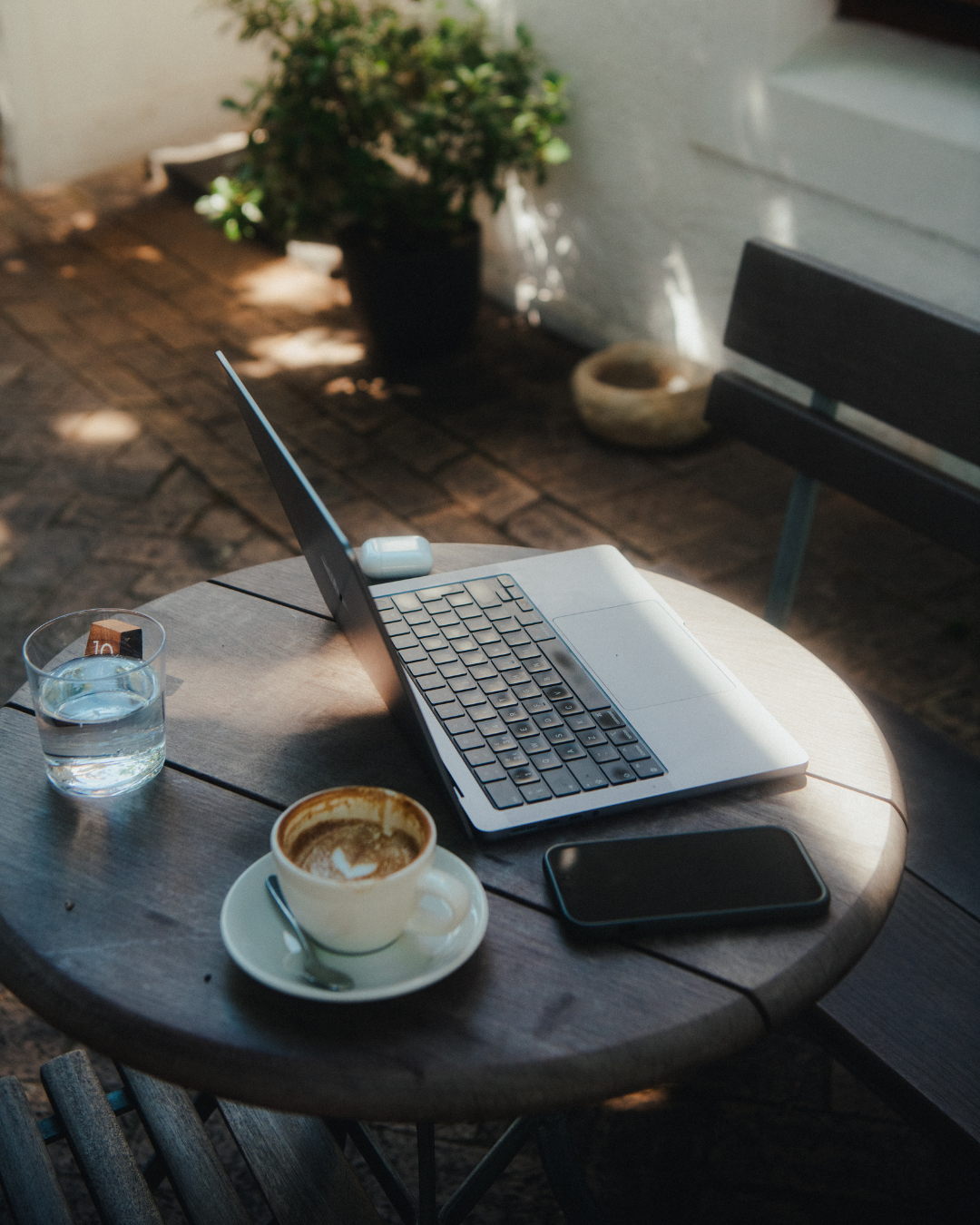 Laptop, coffee, and phone on a table outside Pauline's Cafe in Cape Town