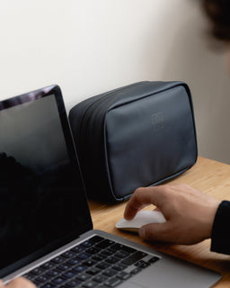 A Midnight Blue Tech Bag on a desk next to a laptop