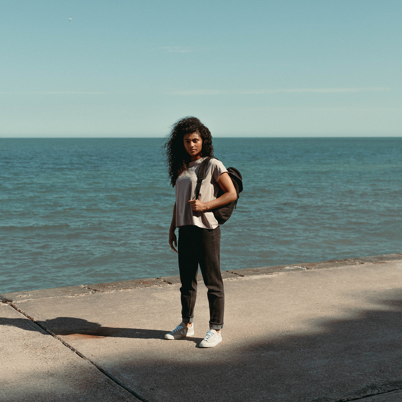 Women wearing The Backpack Mini in All Black by the sea
