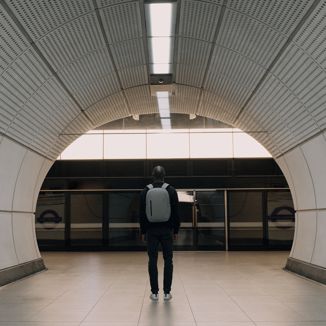 Man wearing The Everyday Backpack in Concrete in a tunnel