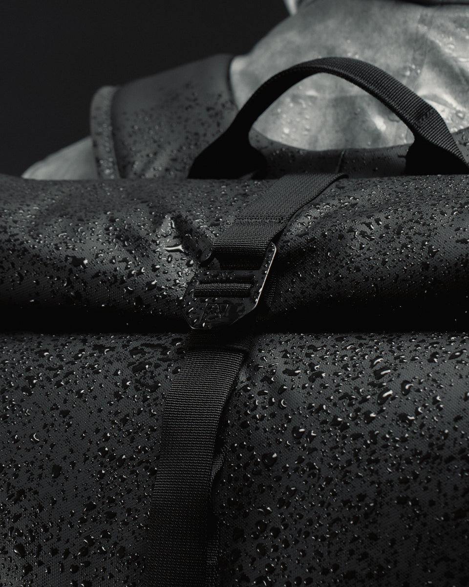 Black Roll Top backpack covered in rain droplets