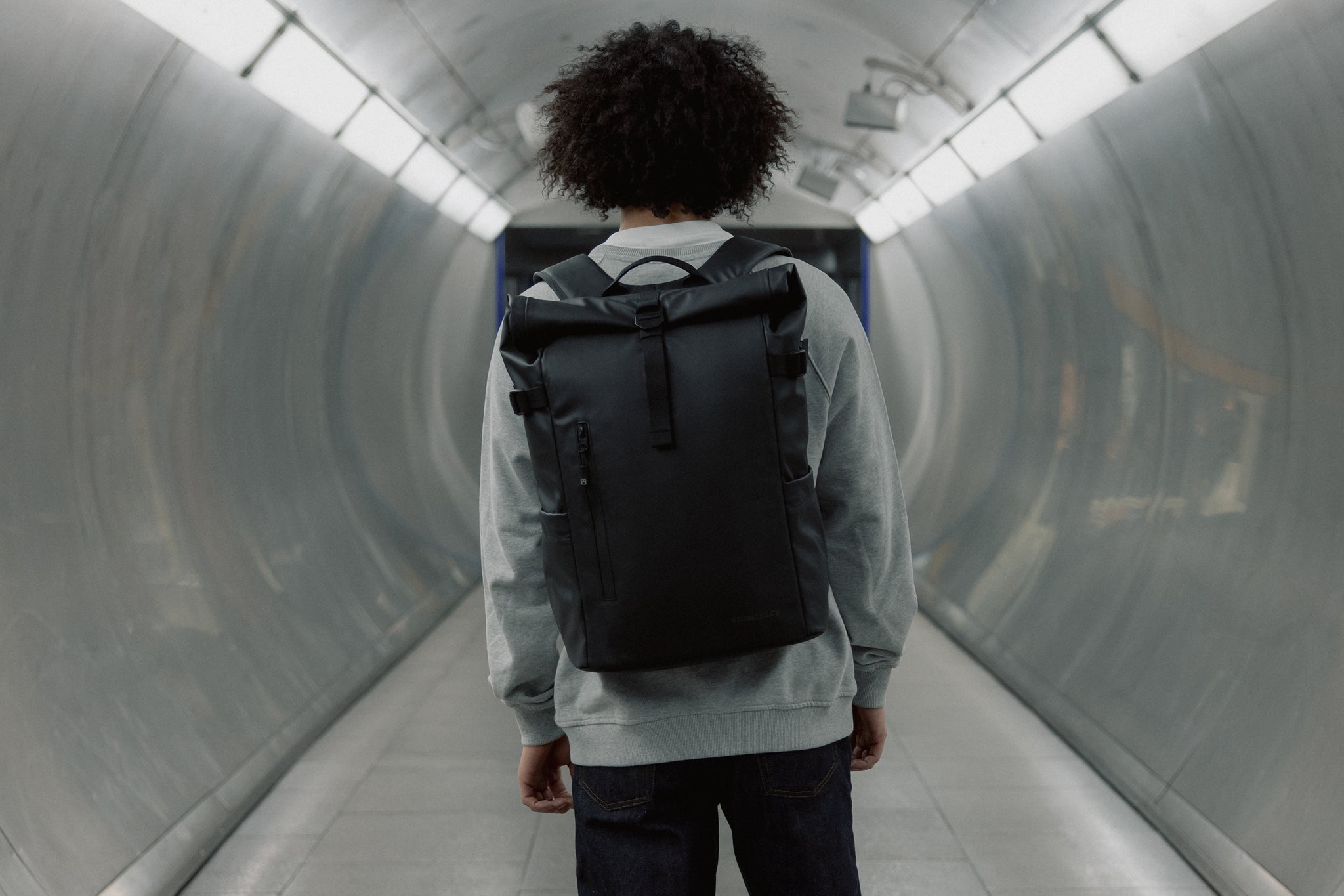 Man wearing the Roll Top 20L in black standing in a tunnel