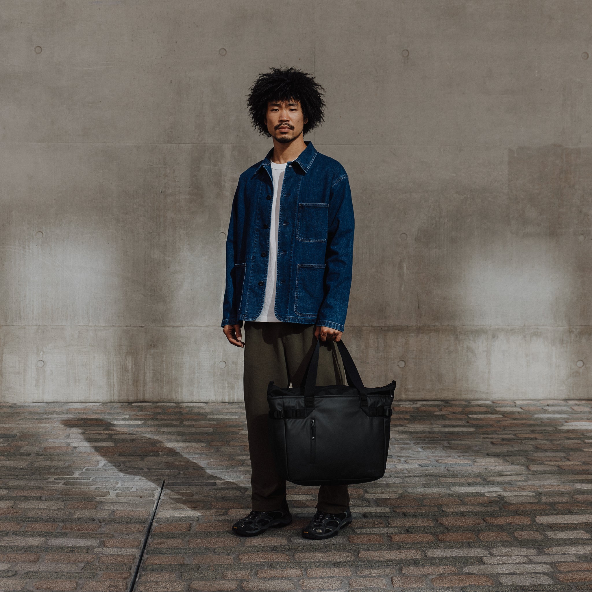 Male carrying The Tote Bag in All Black