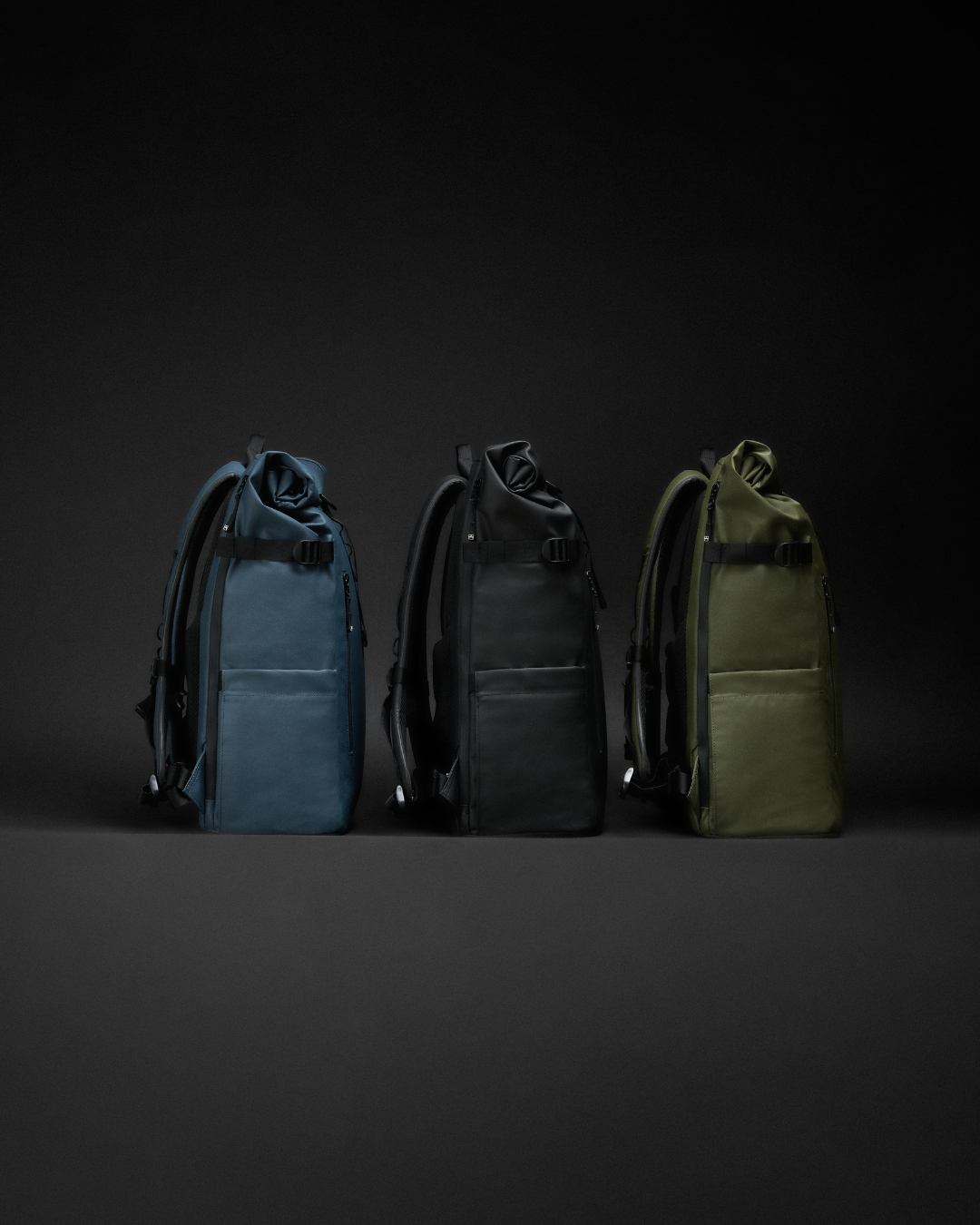 Three Roll Top Backpacks in Tasmin Blue, All Black and Urban Green side by side. 