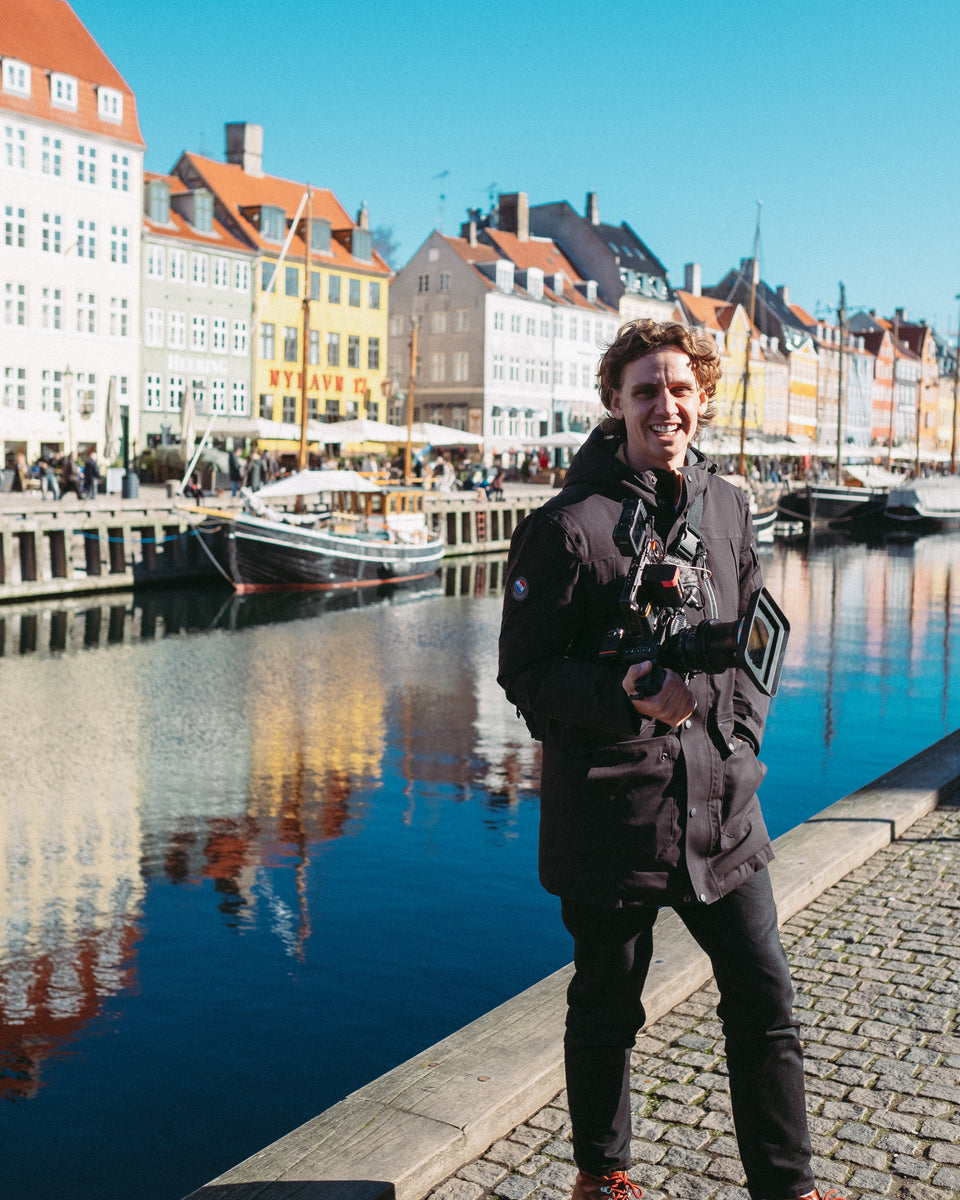 A man standing next to the canal in Amsterdam with a camera in his hand