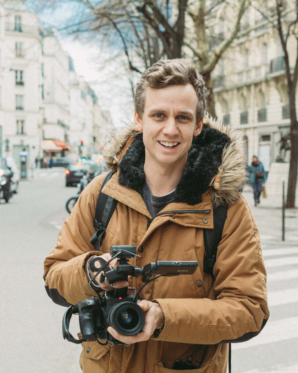 A man from TopJaw, the youtubers, standing in front of the camera holding his camera