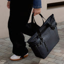 A woman walking carrying a Midnight Blue Laptop Tote 20L down by her side