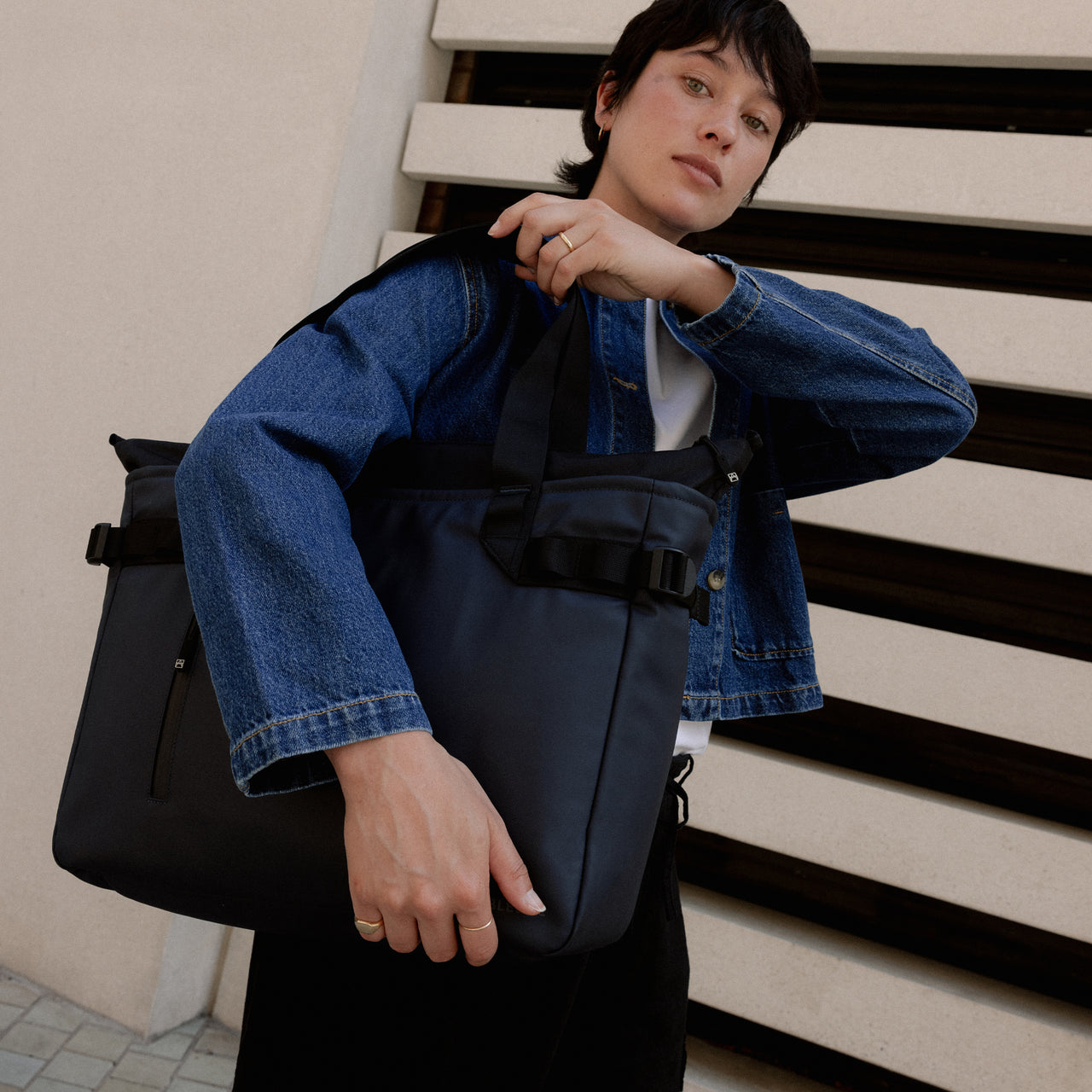 A woman putting a Midnight BlueLaptop Tote 20L over her shoulder
