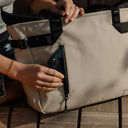 a close up of a woman placing a phone into a Sand Tote Bag