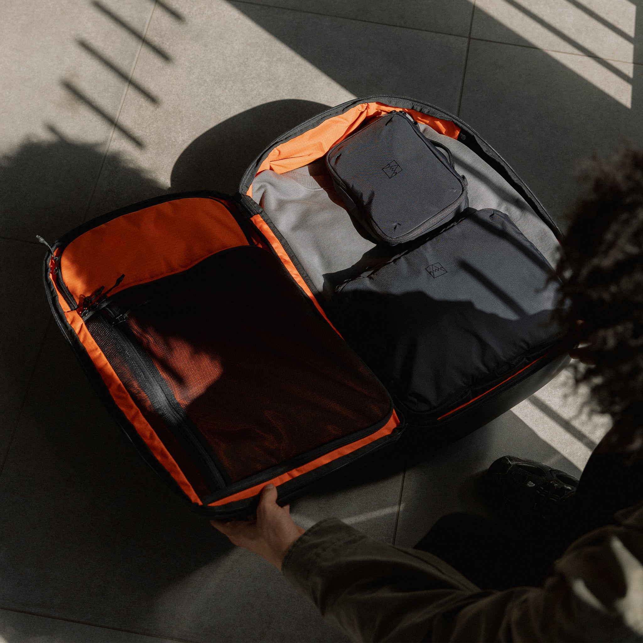A man packing his Travel Backpack 40L in All Black using his Stubble & Co packing cubes