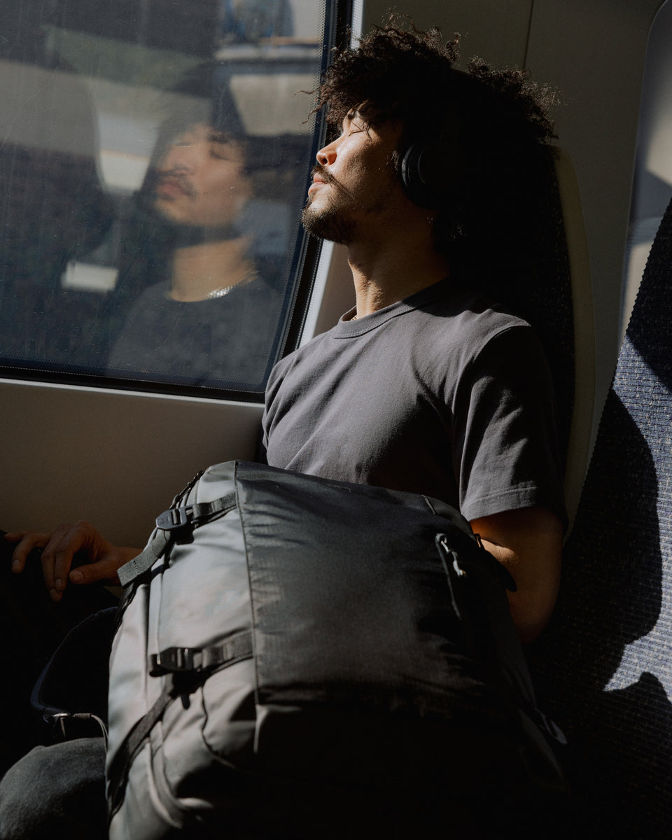 A man sitting on a train with a travel backpack 40l on the chair next to him