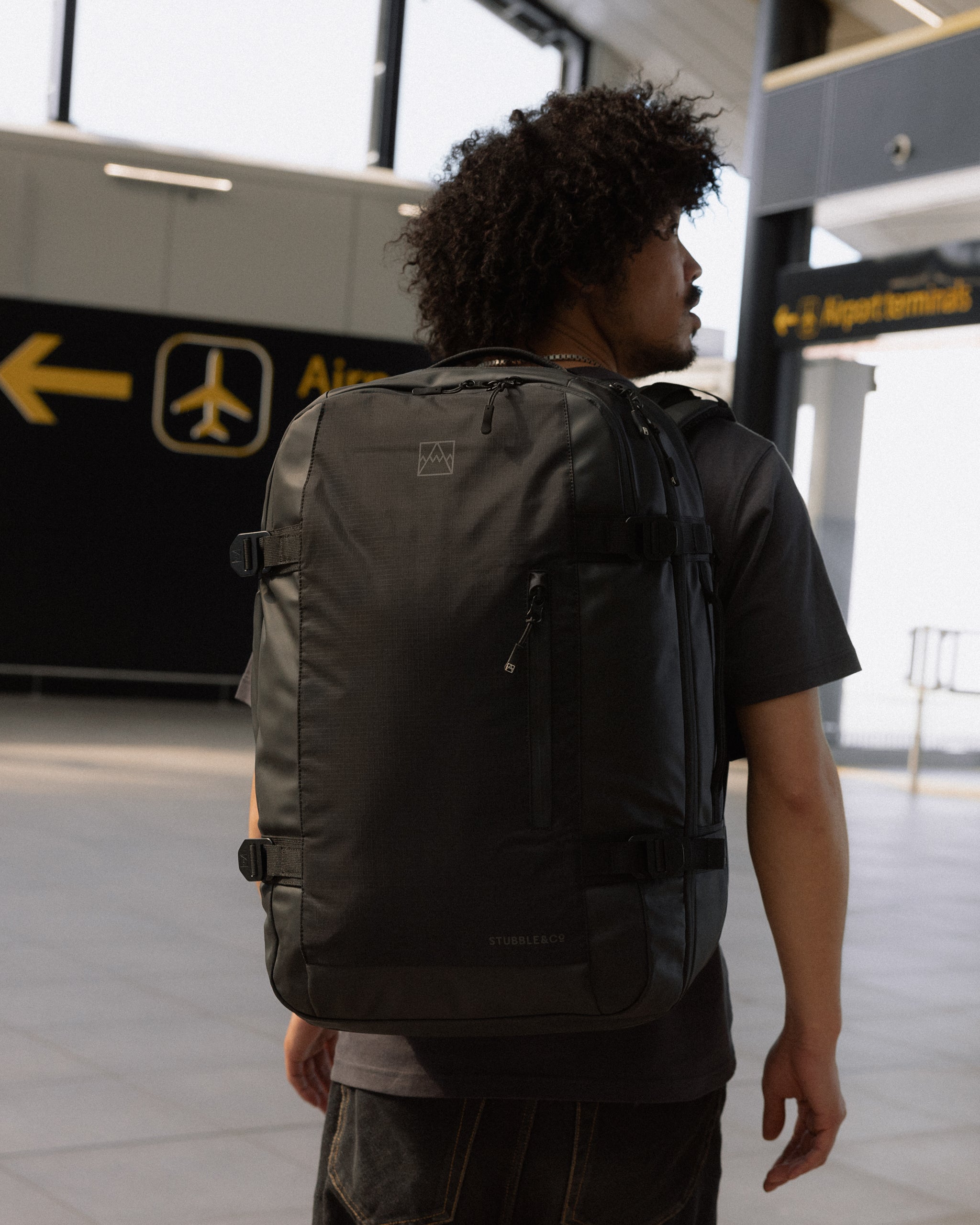 A man standing in an airport with a travel backpack 40l on his back