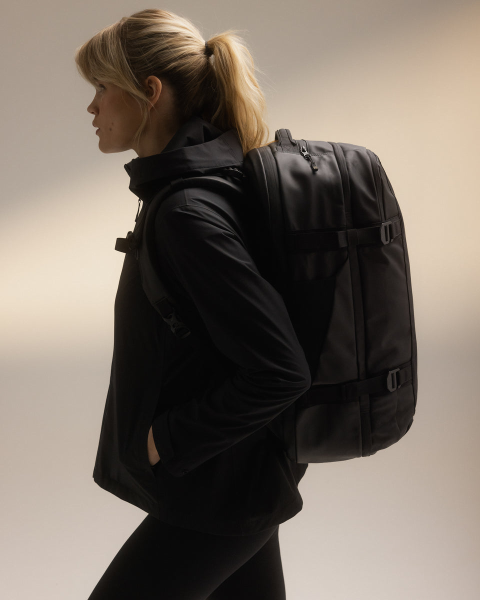 A woman wearing a travel backpack 40l on her back showing the side profile