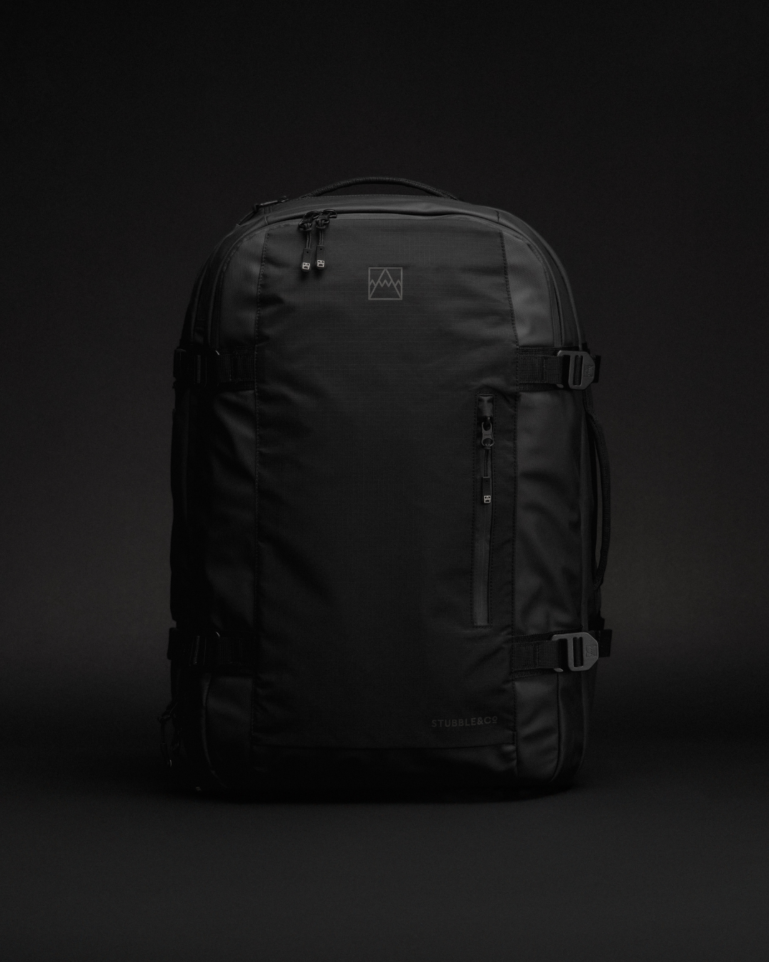 An All Black Travel Backpack, photographed against a black studio backdrop.
