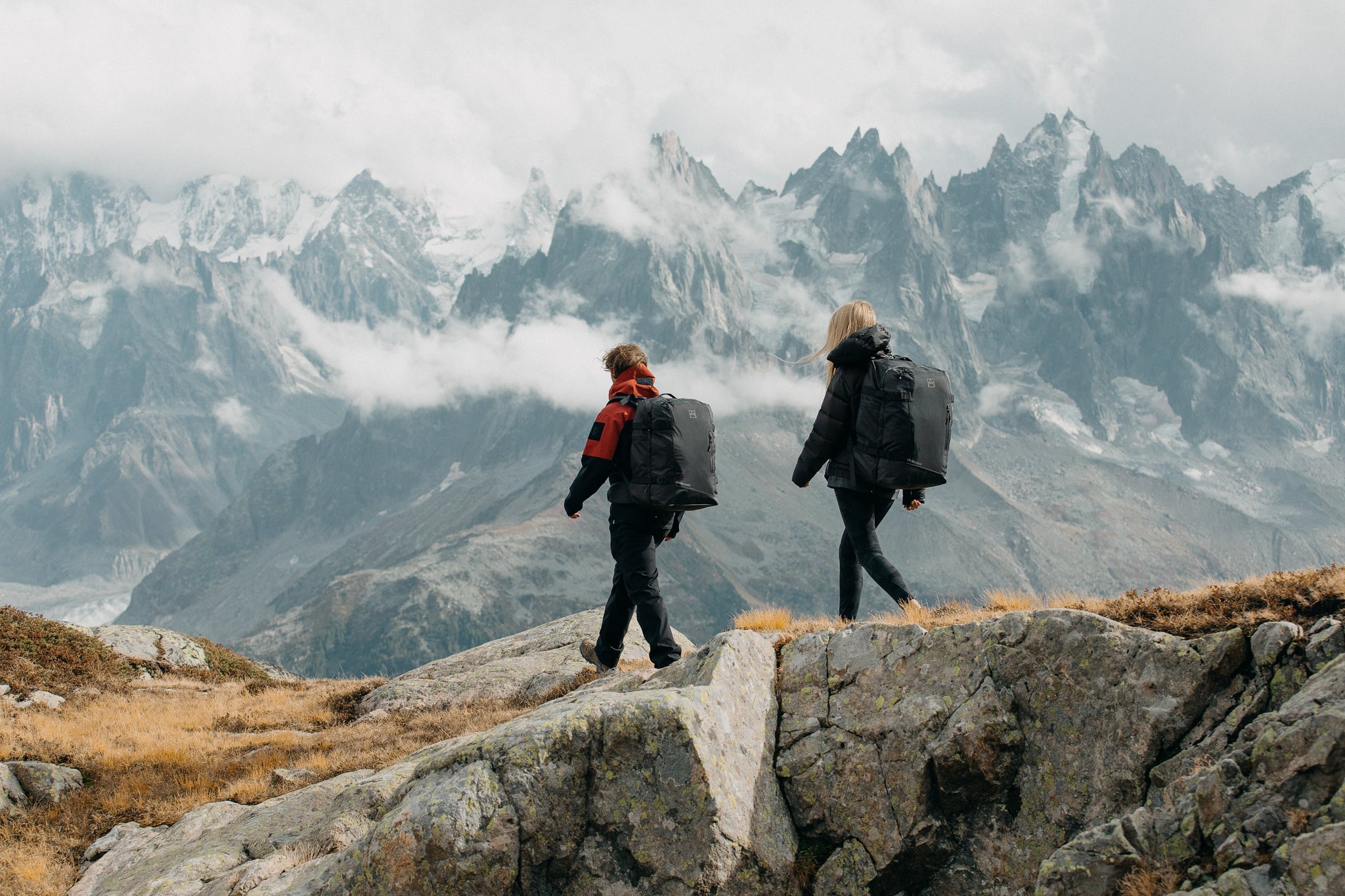 Two people walking on a mountain with outdoor backpacks