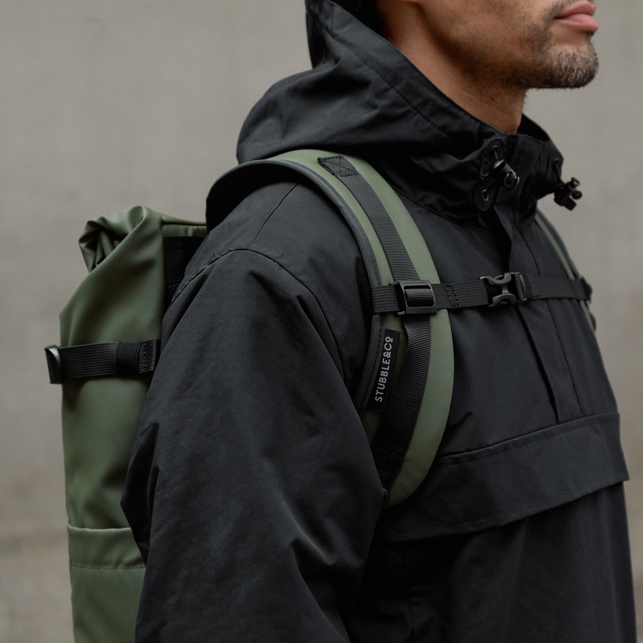 A close up on of the chest straps of an Urban Green Roll Top backpack on a mans back