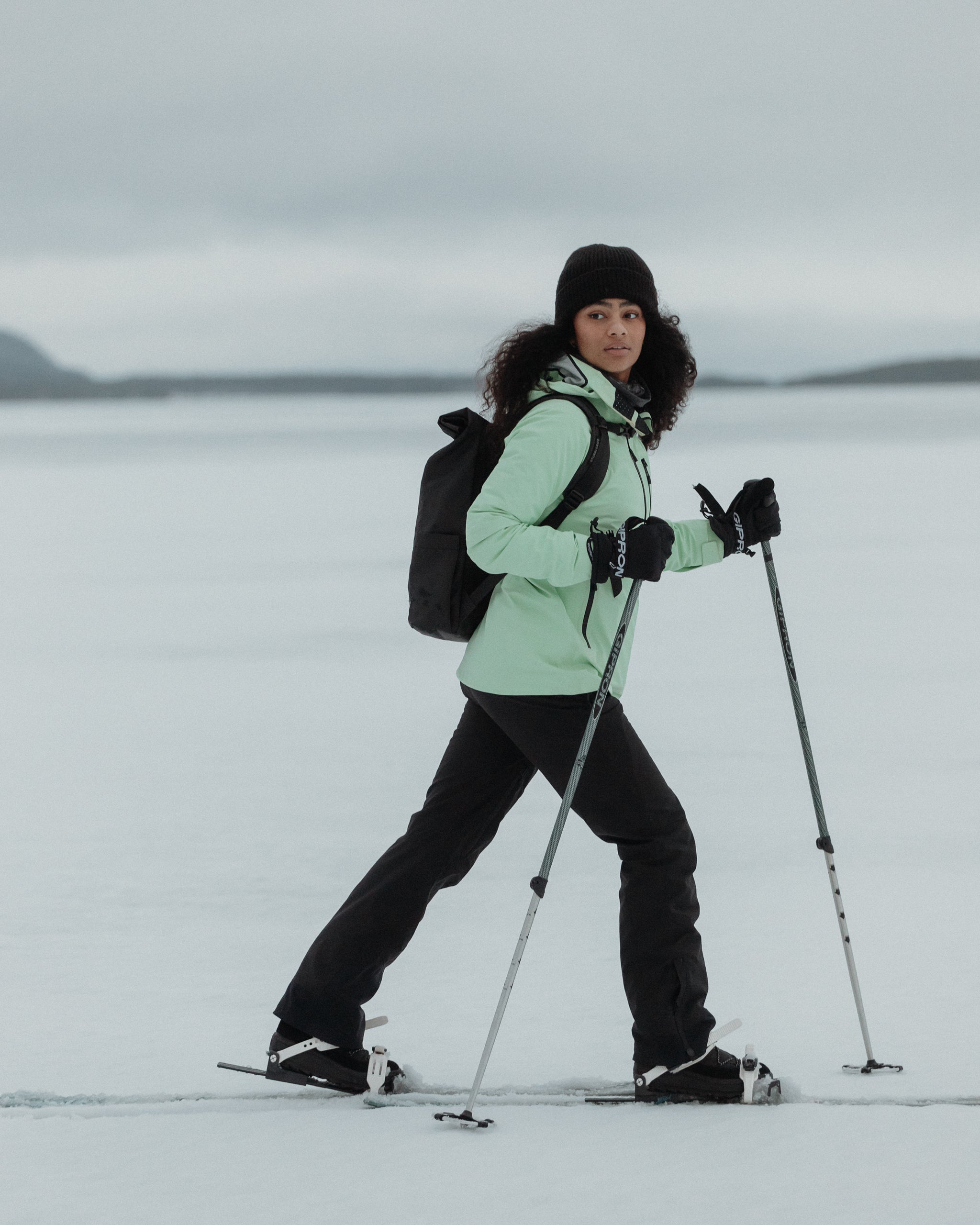 A woman snow walking in Finland with a black Roll Top on her back