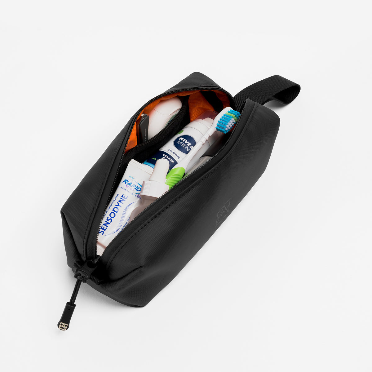 A studio shot of the Wash Bag Mini in All Black with toiletries packed inside