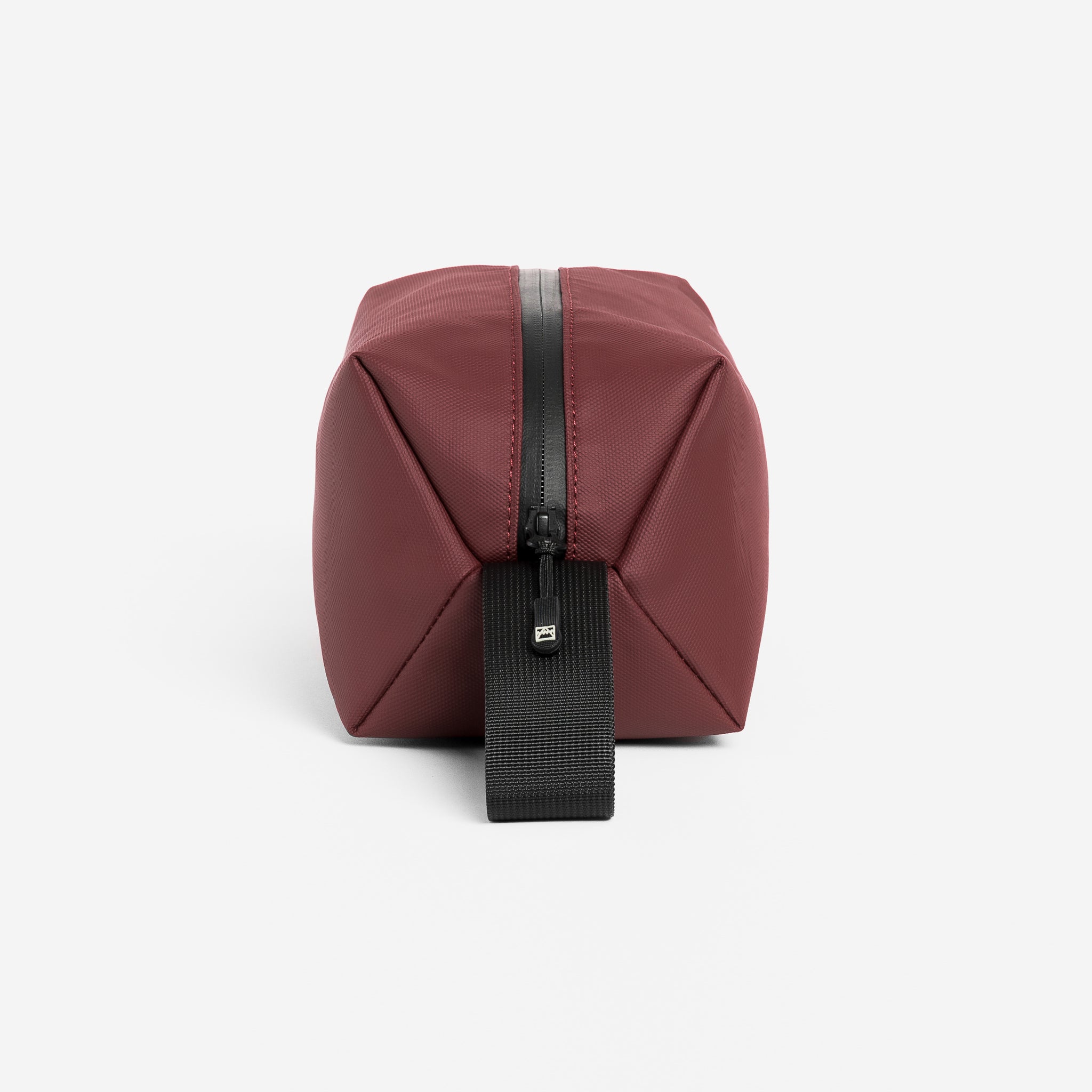A studio shot of the grab handle and end of the Garnet Red Wash Bag