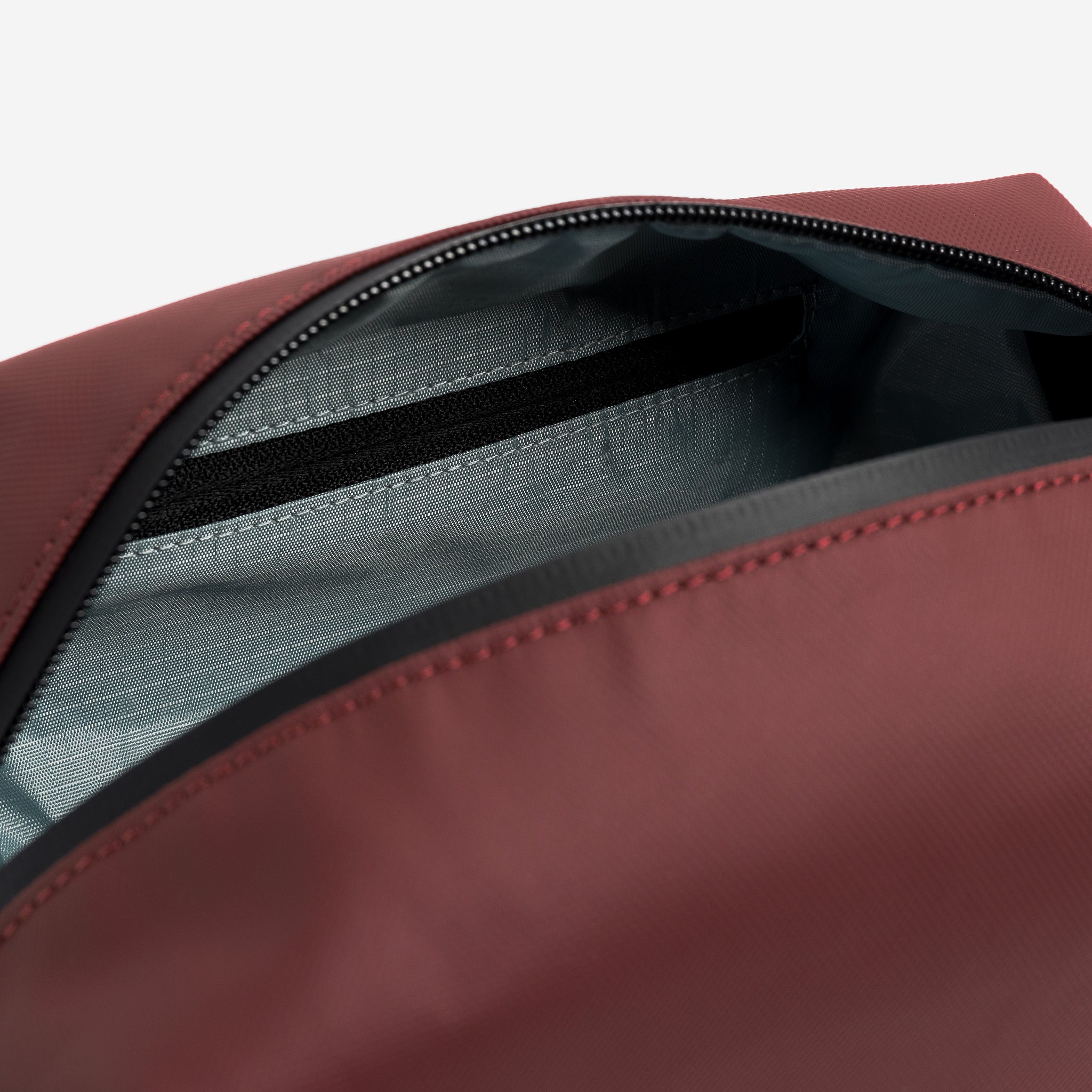 A studio shot of the interior zip pocket in the Garnet Red Wash Bag