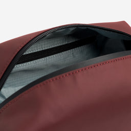 A studio shot of the interior zip pocket in the Garnet Red Wash Bag