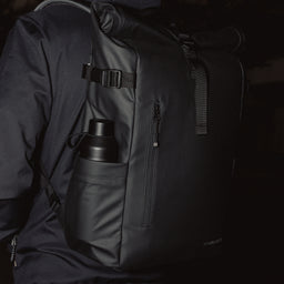 A black roll top 20l with a Stubble and Co and Ocean Bottle bottle in Black in the side pocket