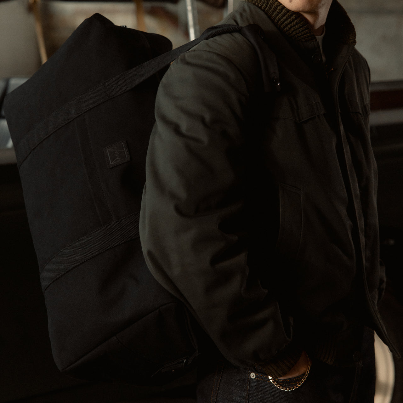 A close up shot of a man wearing the weekender 30l in All Black on his shoulder