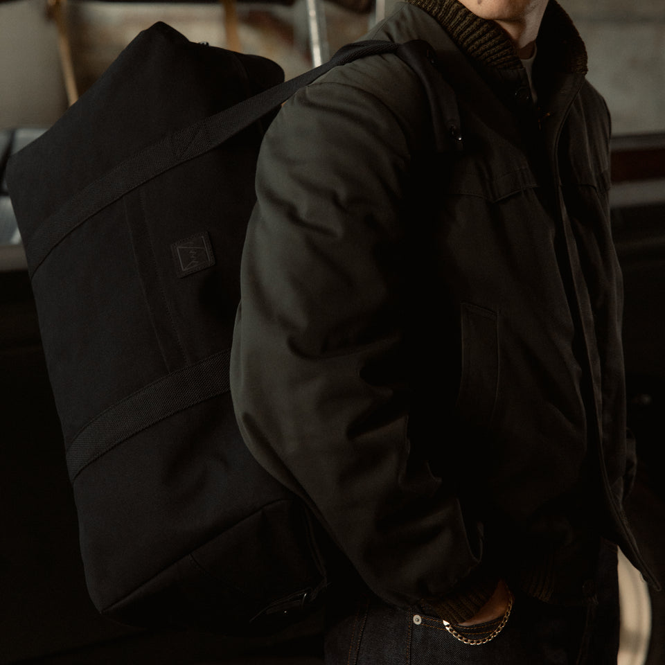 A close up shot of a man wearing the weekender 30l in All Black on his shoulder