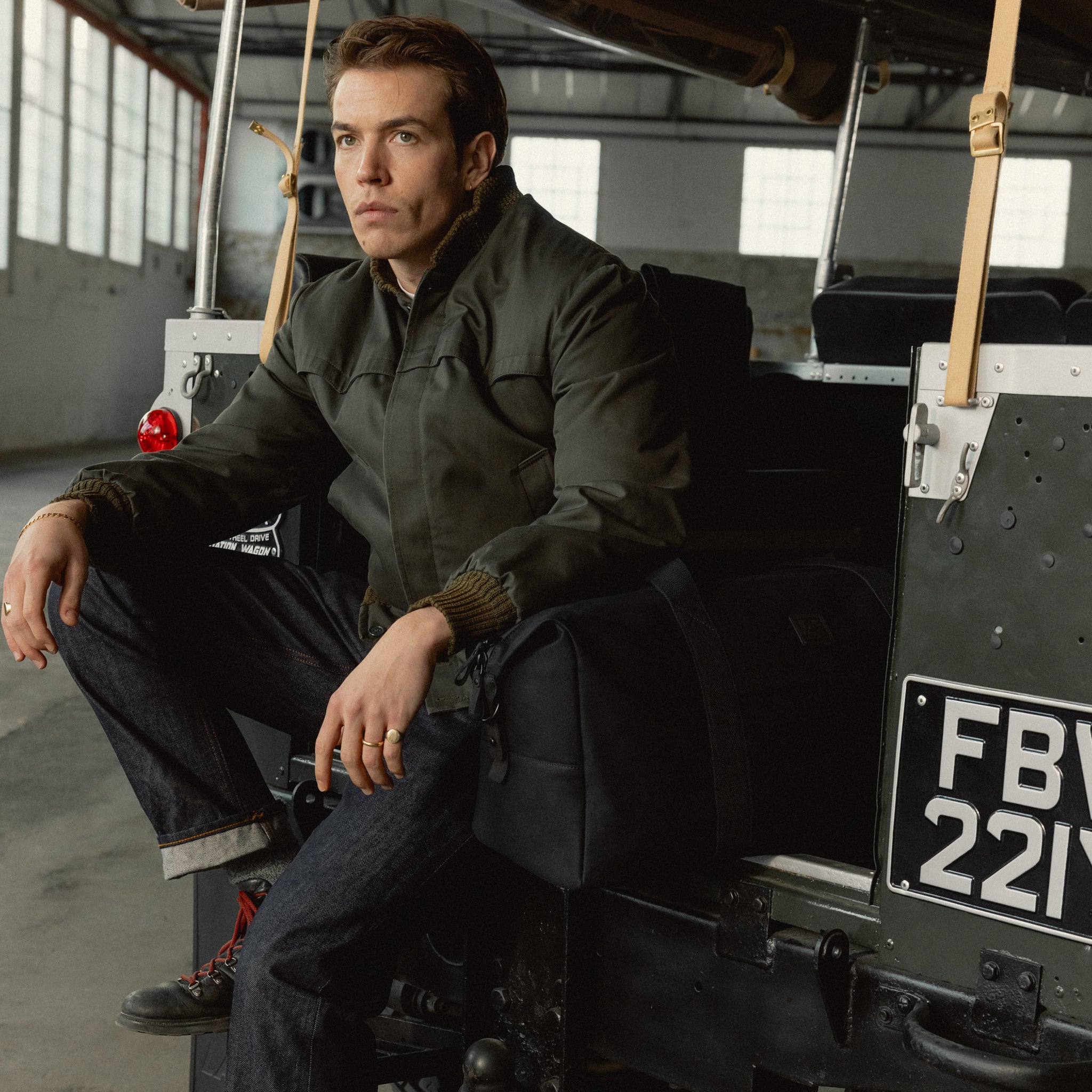 A man sitting on the back of a car with a weekender 30l in All Black next to him