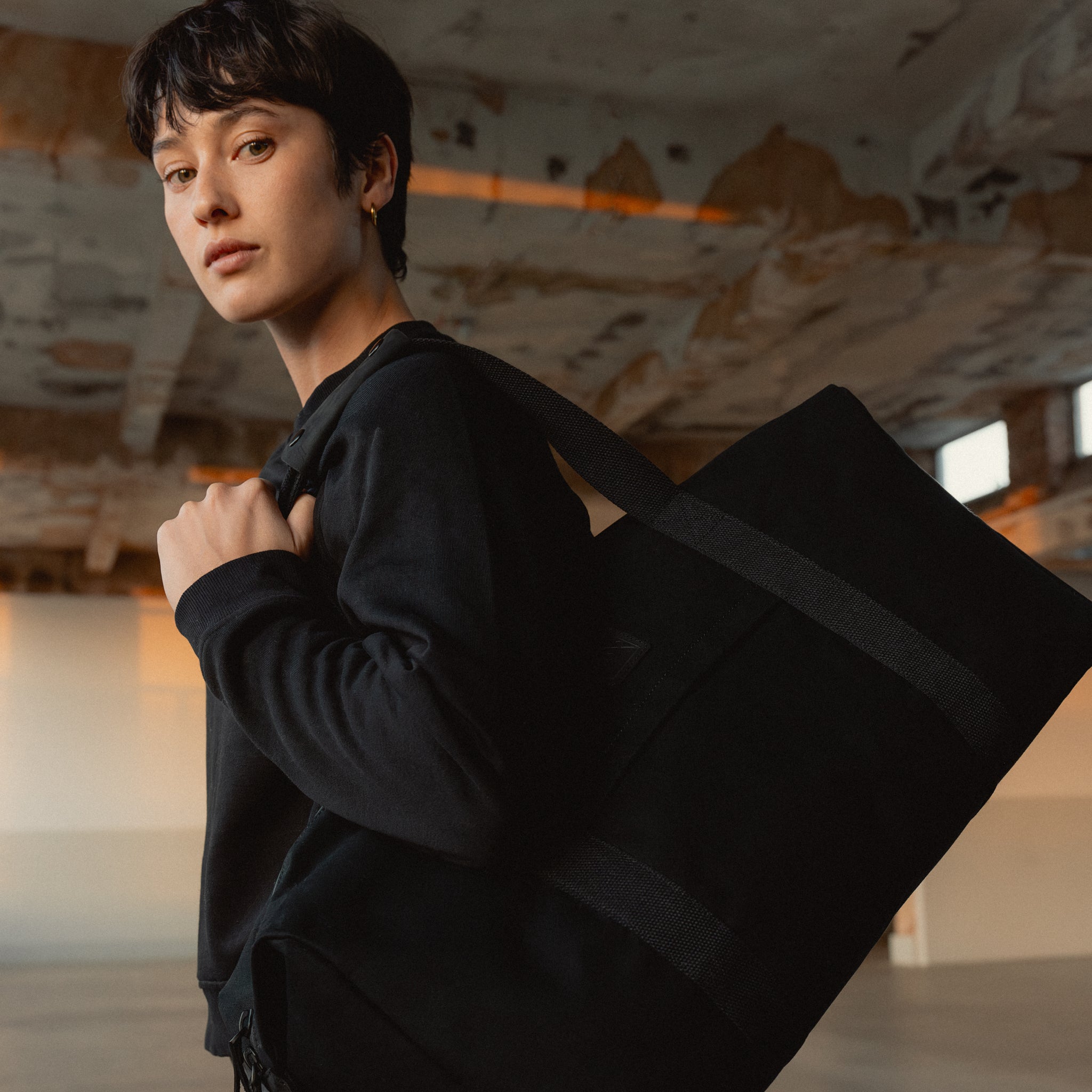 A woman wearing a Weekender 30L in All Black  on her shoulder