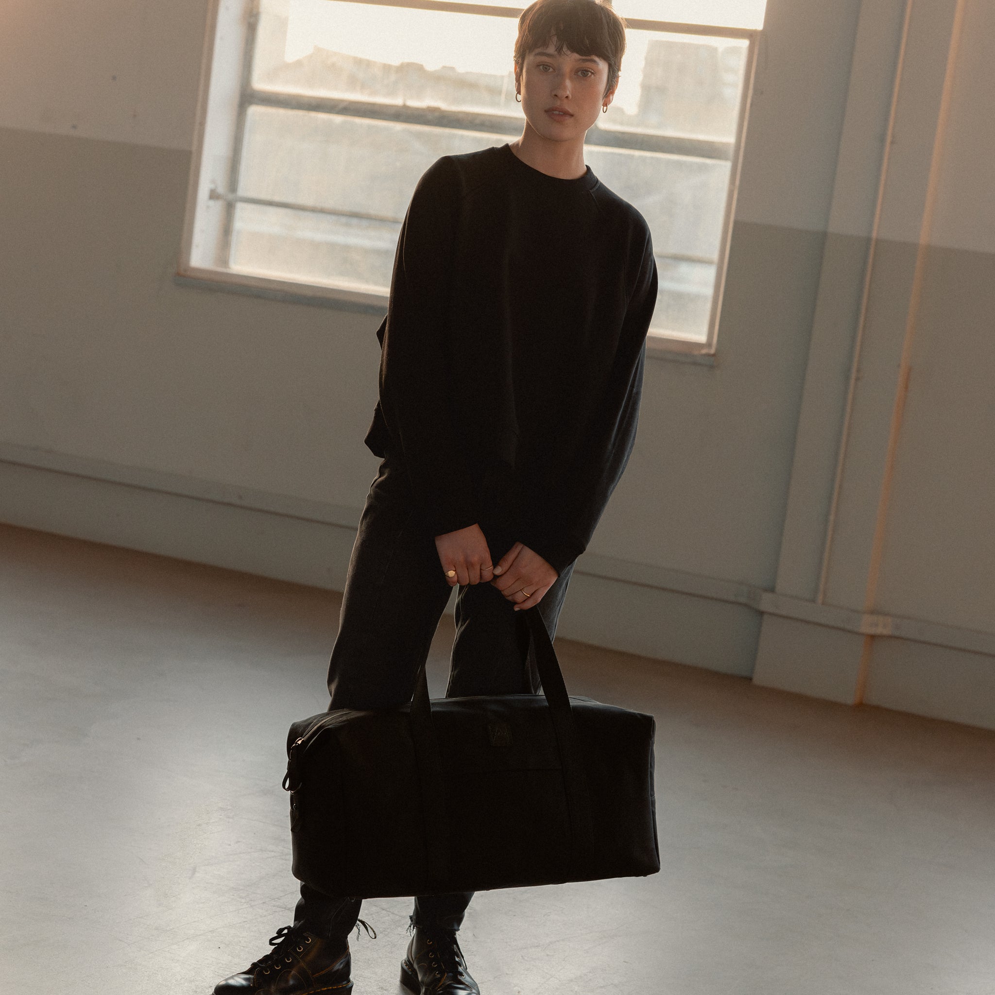 A woman holding a Weekender 30L in All Black down by her side