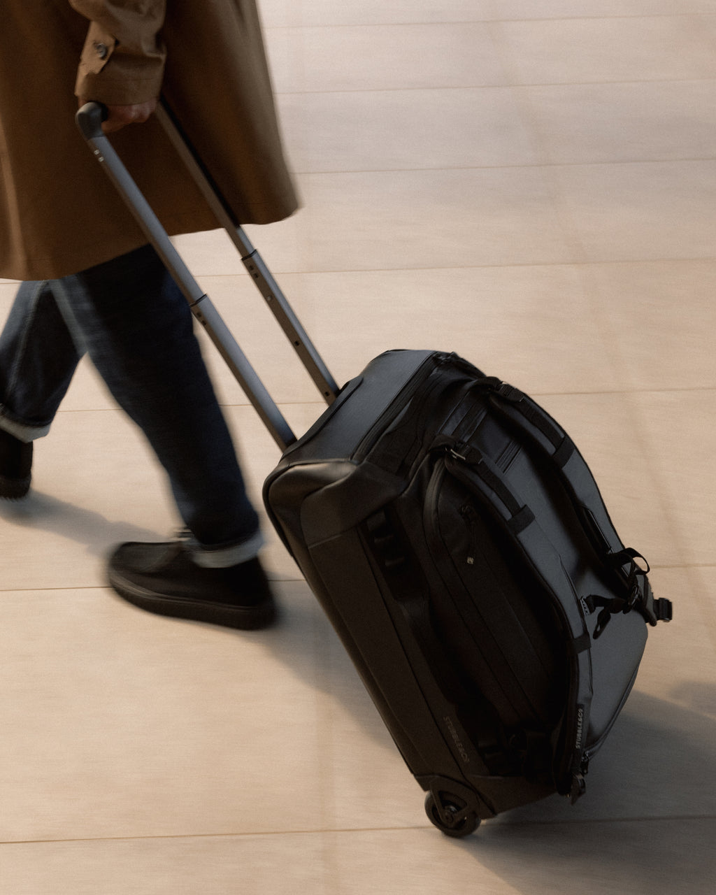 A close up of a Wheeled Kit Bag 40L in black being wheeled behind a man