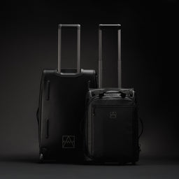 A studio shot of the Wheeled Duffel 80L and 40L side by side showing the front and back in All Black
