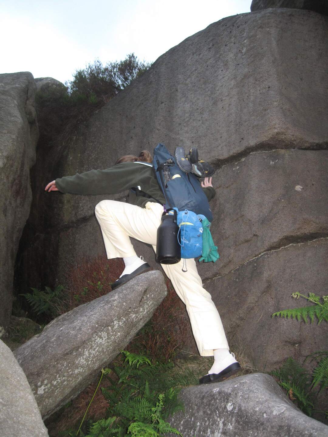 Woman climbing a rocky cliff with a Roll Top backpack