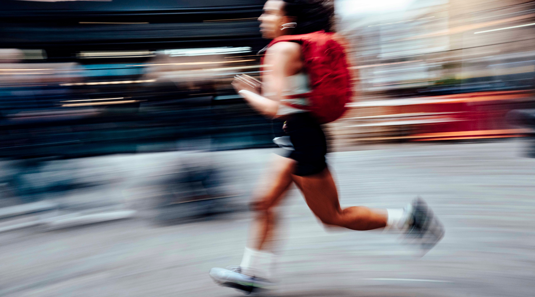 A blurry shot of a woman running wearing a Magma Motion Backpack 20L on her back