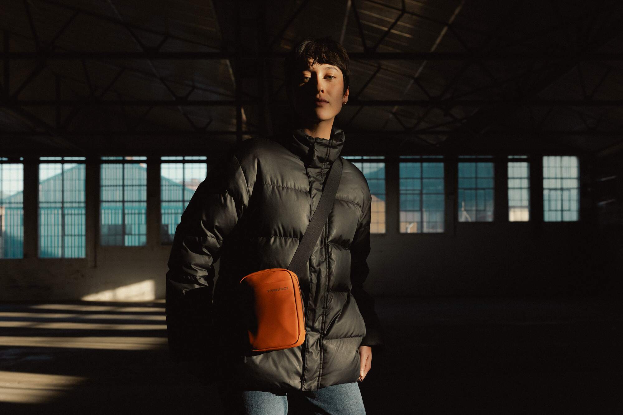 Woman wearing a black puffer jacket with a Rust Shoulder Bag