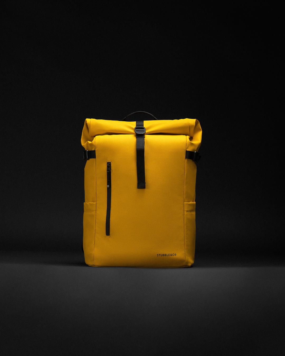 A Roll Top Backpack in Yellow, photographed against a black background.